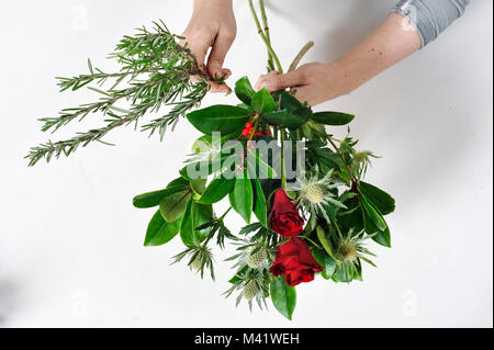 Mazzi di Fiori essendo disposti per una occasione speciale come il giorno di San Valentino. Donna di rifilatura dei gambi dei fiori dopo disponendole. Foto Stock