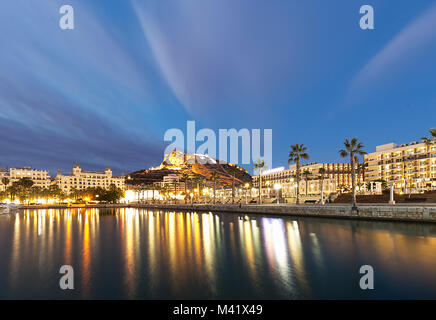 Alicante quando il sole splende con riflessi di luci della città nelle acque del porto Foto Stock