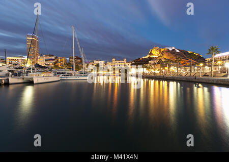 Alicante quando il sole splende con riflessi di luci della città nelle acque del porto Foto Stock