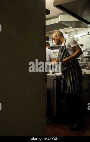 Uno chef lavorando sui suoi piedi in un ristorante di cucina a Bristol, Inghilterra Foto Stock