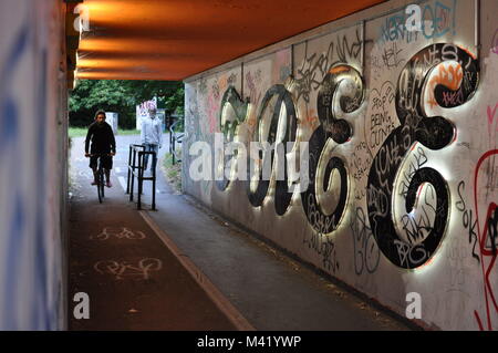 Un uomo in sella ad una bici attraverso un sottopassaggio tunnel con lettere compitazione 'libero' Foto Stock