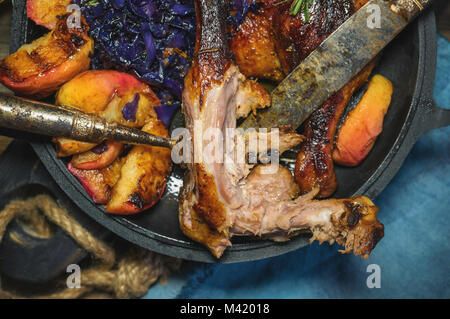 Marinata di pezzi di anatra alla griglia con cavolo rosso, cipolla e mele alla griglia e servita in stile rustico. Semi-mangiato. Il concetto di cibo delizioso. C Foto Stock