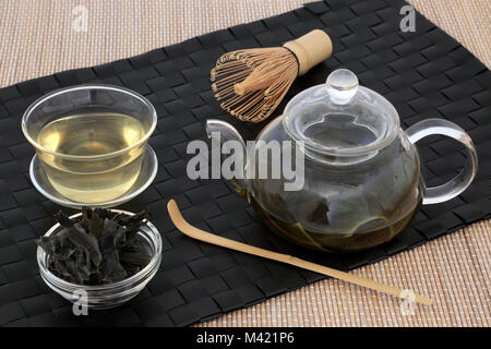 Sencha giapponese alghe wakame tè con vetro teiera e tazza, foglie secche,  agitatore e frusta su sfondo di bambù. Ha molti benefici per la salute Foto  stock - Alamy