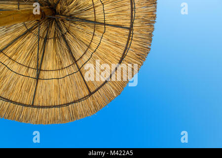 Ombrellone di paglia contro il cielo blu Foto Stock