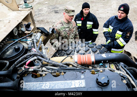 Stati Uniti Il personale dell'esercito Sgt. Clayton piani (a destra), un Daytona, Ohio nativo e manutenzione sul campo di capo del team con l'ottantaduesima brigata battaglione ingegnere, 2° Brigata corazzate contro la squadra, 1a divisione di fanteria, mostra un membro del polacco 5430rd militare dei vigili del fuoco e un emergency first responder il motore di un agguato Mine-Resistant veicolo protetto in Zagan, Polonia nel Febbraio 9, 2018. Piani e la sua unità sono parte di una multinazionale di esercizio progettata per aumentare l'interoperabilità durante l Atlantic risolvere. (U.S. Esercito foto di Spc. Hubert D. Delany III / 22nd Mobile degli affari pubblici distacco) Foto Stock