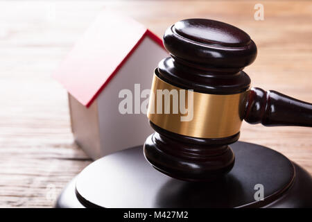 Close-up del modello di casa con martello sul tavolo di legno Foto Stock