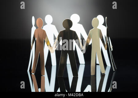 Close-up di carta tagliato figure umane su sfondo grigio Foto Stock