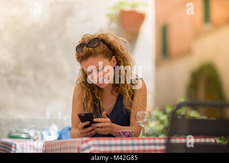 Giovane femmina adulta seduto presso il café con lo smartphone Foto Stock