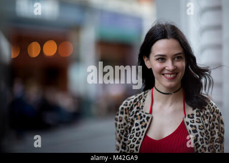 Giovane femmina adulta camminando per strada di sera Foto Stock