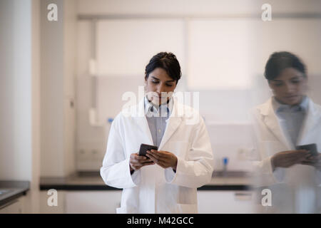 Donna scienziato utilizza lo smartphone in laboratorio Foto Stock