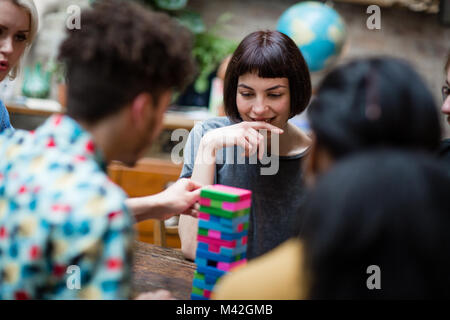 Gruppo di amici a giocare gioco retrò in pub Foto Stock