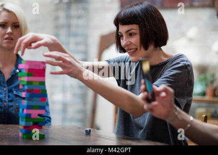 Gruppo di amici a giocare gioco retrò in pub Foto Stock