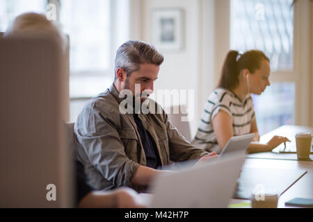 I freelance che lavora in un ufficio condiviso deskspace Foto Stock