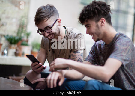 Due amici maschi guardando uno smartphone Foto Stock