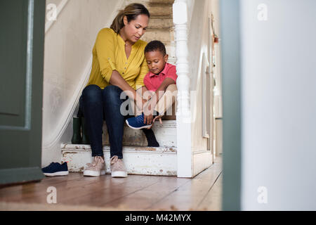 La mamma ad aiutare il figlio con le sue scarpe Foto Stock