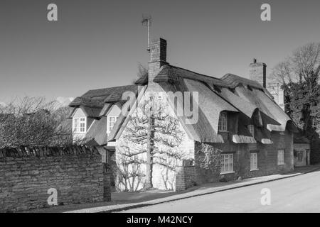 Un'immagine monocromatica di un cottage in pietra con il tetto di paglia. Foto Stock