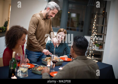 Maschio adulto che serve il pranzo di Natale per gli amici Foto Stock