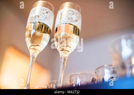 Due bicchieri di champagne con gli anelli di nozze sul fondo fotografato dall'angolo inferiore per una profondità di campo ridotta Foto Stock