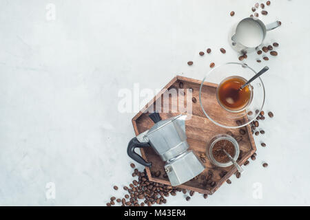 Vassoio in legno con la Moka pot, tazza di espresso, caffè macinato il vaso e i chicchi di caffè su un cemento bianco sfondo con copia spazio. La testata con la preparazione del caffè Foto Stock