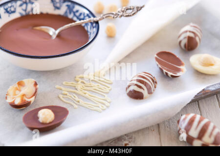 Homemade milk and white chocolate Easter eggs on a rustic table. Foto Stock