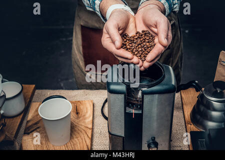 Chiudere l immagine di un uomo mettendo i chicchi di caffè in un caffè machi Foto Stock