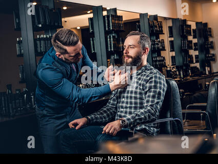 Elegante grooming barbiere un uomo con la barba in una berlina. Foto Stock