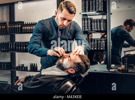 Elegante grooming barbiere un uomo con la barba in una berlina. Foto Stock