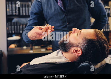 Elegante grooming barbiere un uomo con la barba in una berlina. Foto Stock