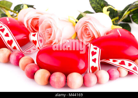 Cuore rosso candele, collana in legno, nastro e rose su sfondo bianco. Foto Stock