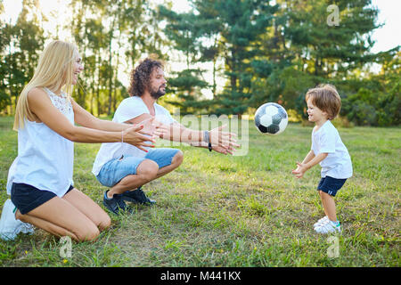 La famiglia gioca con una palla nel parco. Foto Stock