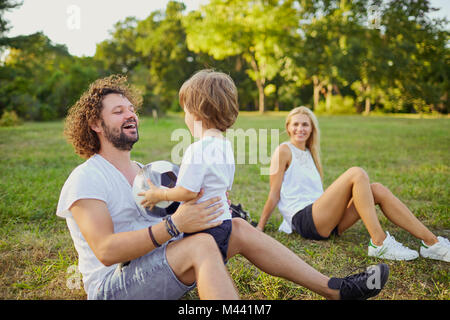 La famiglia gioca con una palla nel parco. Foto Stock