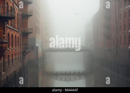 Il vecchio magazzino del distretto di misteriosa nebbia. Canale per acqua ad Amburgo, in Germania. Foto Stock