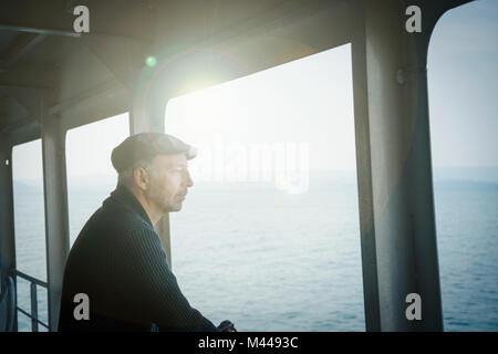 L'uomo sul traghetto che guarda lontano fuori della finestra Foto Stock