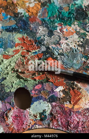 Dettaglio del disordine artista tavolozza e pennello in artists studio, close up Foto Stock