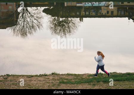 Sinuosa giovane femmina runner in esecuzione su Riverside Foto Stock