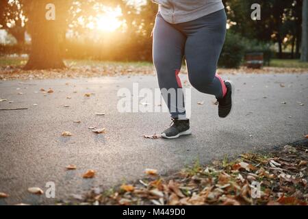 Sinuosa giovane femmina runner acceso nel parco, vita scende Foto Stock