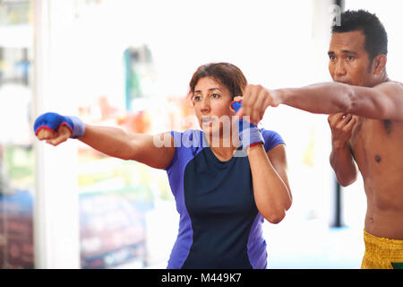 Donna matura la pratica di boxe punch con maschio del trainer in palestra Foto Stock