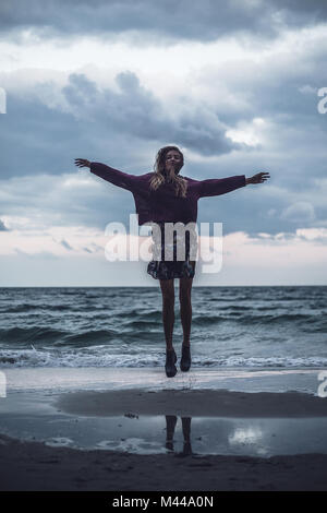 Ritratto di giovane donna salto sulla spiaggia al tramonto, Oblast di Odessa, Ucraina Foto Stock