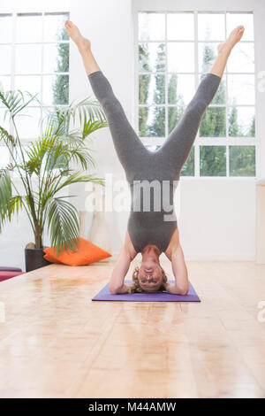 La donna in casa, fare yoga, facendo headstand, in posizione di yoga Foto Stock