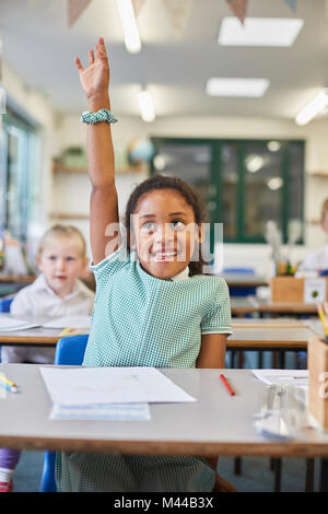 Schoolgirl con la mano fino in aula presso la scuola primaria Foto Stock