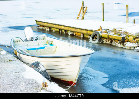 Bianco aperto motoscafo bloccato nel ghiaccio da un molo. Foto Stock