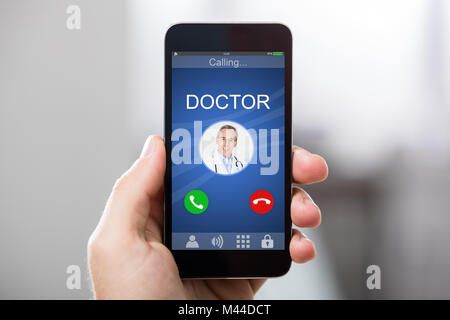 Close-up di una mano azienda Smart Phone con medico della chiamata in arrivo sul display Foto Stock