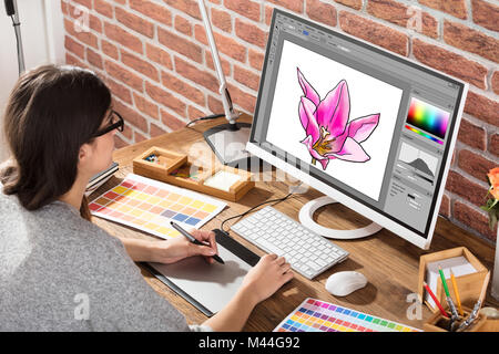 Angolo di alta vista del designer femmina disegno fiore sul computer utilizzando tavoletta grafica in ufficio Foto Stock