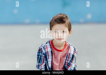 Vista frontale di un 6 anno vecchio ragazzo in posa all'aperto e prendendo una pausa Foto Stock