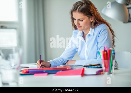 Giovane donna fashion designer che lavora alla scrivania in ufficio Foto Stock