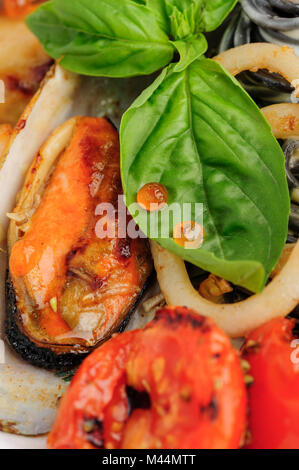 Pasta di colore nero con frutti di mare e basilico Foto Stock