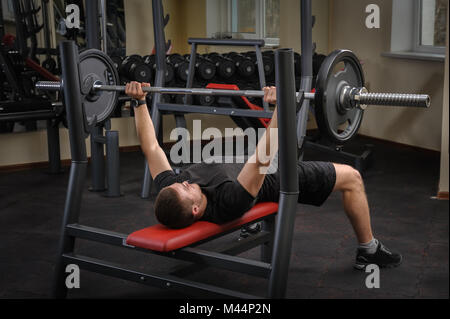 Giovane uomo facendo la pressa da banco allenamento in palestra Foto Stock