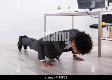 Giovane Imprenditore facendo spingere in alto sul pavimento nel luogo di lavoro Foto Stock