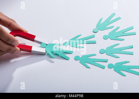 Close-up di un imprenditore di mano azienda rosso del magnete a ferro di cavallo per attrarre candidati della carta sulla scrivania Foto Stock