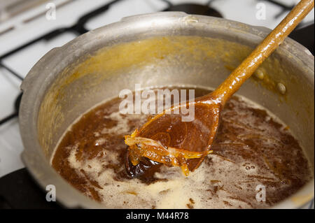 Fare marmellata fatta in casa con Saville arance di cottura in cui vi è un rischio elevato di zucchero mix di marmellata bollente sul fornello se dimentica di mantenere in agitazione Foto Stock